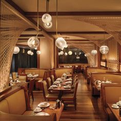 the interior of a restaurant with wooden tables and chairs, white plates and silverware