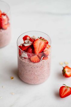 two small cups filled with fruit on top of a white table next to strawberries