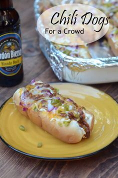 a hot dog sitting on top of a yellow plate next to a bottle of beer