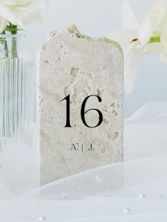 two vases with white flowers in them and the number sixteen on one stone block