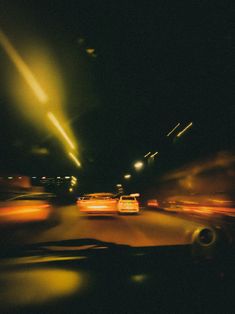 cars driving down the road at night with street lights in the background and blurry image