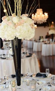 a vase filled with white flowers on top of a table covered in plates and silverware