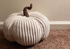 a knitted pumpkin sitting on the floor next to a wall and carpeted area