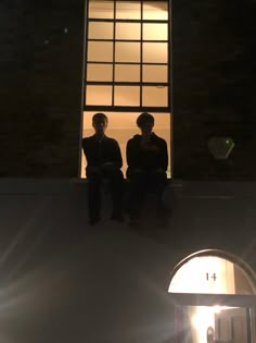 two people sitting on a ledge in front of a window with the sun shining through