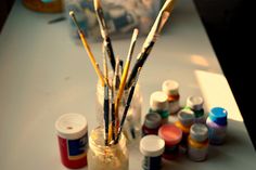 an assortment of paint and brushes sitting on a table