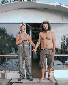 two men holding hands while standing in front of a building with an open glass door