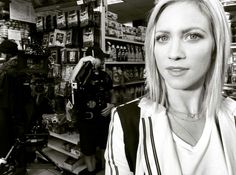 a black and white photo of a woman standing in front of a store with cameras