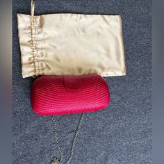 a pink purse sitting on top of a gray floor next to a white bag and chain