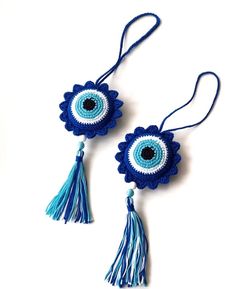 two blue and white crocheted earrings with tassels on the ends, one has an evil eye