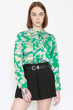 Introducing the SNOW XUE GAO Silk Floral Prints Green Blouse—a harmonious blend of sophistication and playfulness. This button-down beauty features a shirt collar with a chic necktie, while pleats in the front opening add a touch of elegance. The playful floral pattern in vibrant yellow makes it uniquely perfect for both work and special events. Crafted from luxurious silk, this blouse offers comfort and standout style. Effortlessly elevate your look with SNOW XUE GAO, where uniqueness and ease Beauty Features, American Fashion Designers, Nova York, Asian American, Green Blouse, Zambia, Office Wear, Shirt Collar, American Style