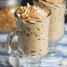 two glasses filled with dessert sitting on top of a table