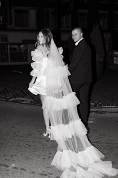 black and white photograph of bride and groom walking down the street at night in tuxedo