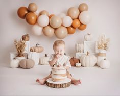 a baby sitting in front of a cake surrounded by balloons