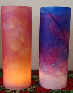 three different colored candles sitting next to each other on top of a carpeted floor