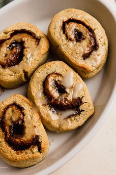 four cinnamon rolls with icing on a white plate