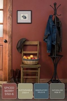 a wooden chair sitting in front of a red wall next to a coat rack and door