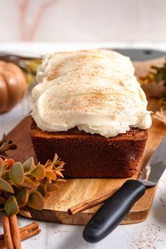 a loaf of cake with frosting sitting on top of a cutting board next to some cinnamon sticks