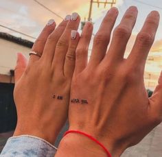 two people with matching tattoos holding their hands up to each other while the sun is setting