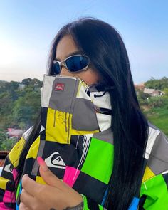 a woman with long black hair and sunglasses on her face holding up a cell phone