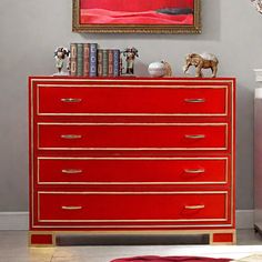 a red chest of drawers in a room with a painting on the wall above it