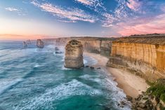 an aerial view of the ocean and cliffs at sunset, with waves crashing on the beach