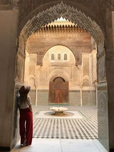 a woman standing in front of a building with an archway and tiled floor, looking into the distance