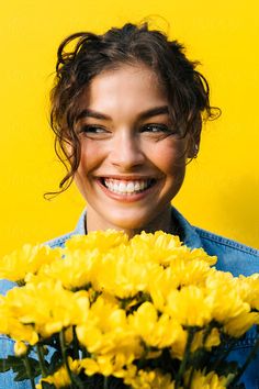 a smiling woman holding a bouquet of yellow flowers by luma studio for stockstation