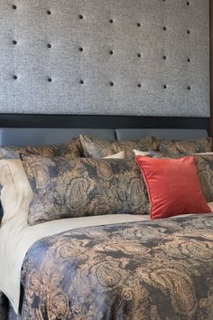 a bed with a gray headboard and red pillows on it's sides is shown