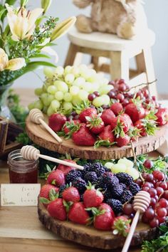 three wooden trays filled with different types of fruit and honey on top of a table