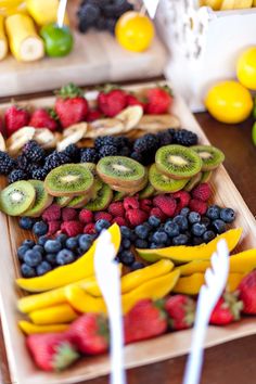 various fruits are displayed on trays with strawberries, kiwis, and lemons