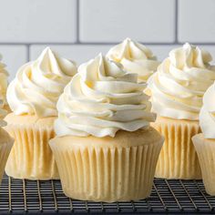 cupcakes with white frosting sitting on a cooling rack