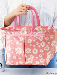 a woman is holding a pink bag with daisies on it and she has her hands in the pocket