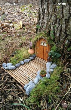 a small house made out of rocks and wood in the woods next to a tree