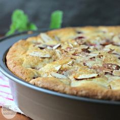 a close up of a pie in a pan on a wooden table with green leaves