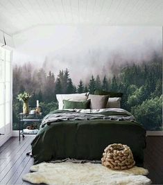 a large bed sitting in a bedroom next to a forest wallpaper covered in fog