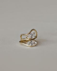 two diamond rings sitting on top of each other in front of a gray background,