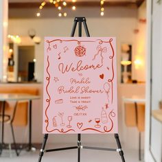 a welcome sign is on an easel in front of a table with chairs and lights