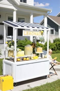 an outdoor lemonade stand on the side of a road with yellow and white decorations