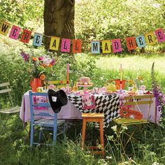 a table set up in the middle of a field with flowers and decorations on it