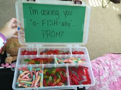 an open plastic box filled with lots of different colored candies next to a sign that says i'm asking you o - fish ally prom