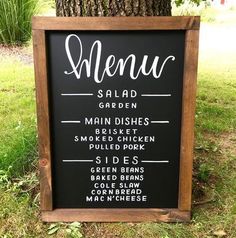 a menu sign sitting next to a tree in the grass with other signs on it