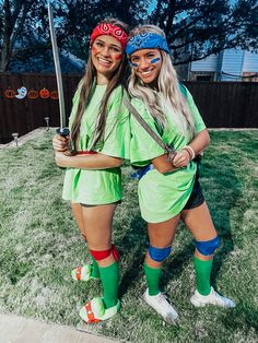 two girls in costumes standing next to each other on the grass with their arms around one another