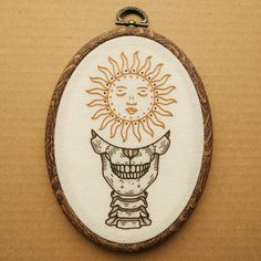 the embroidery is hanging on the wall and it has an image of a smiling sun