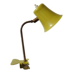 a yellow table lamp with a metal base and an arm that has a light bulb on it