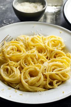 two white plates filled with pasta on top of a table next to a glass of water