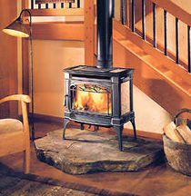 a wood burning stove sitting in the middle of a living room next to a stair case