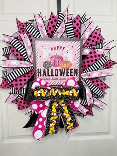 a pink and black halloween wreath with polka dots, pumpkins and stripes on it