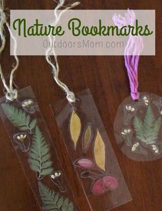 three bookmarks with leaves and acorns in them on a wooden table next to yarn