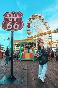 a woman is standing in front of a sign that says route 66 and a ferris wheel