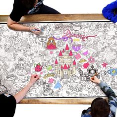 three people drawing on a large poster with disney castle in the background and other characters around it